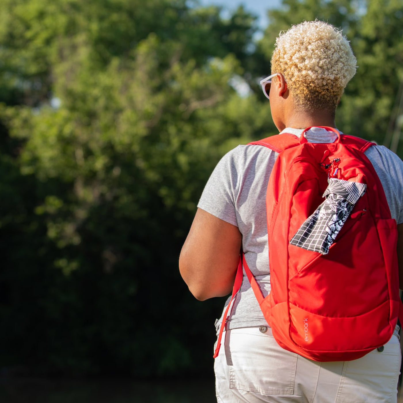A person wearing a backpack with a pStyle in a pCase clipped to it. 